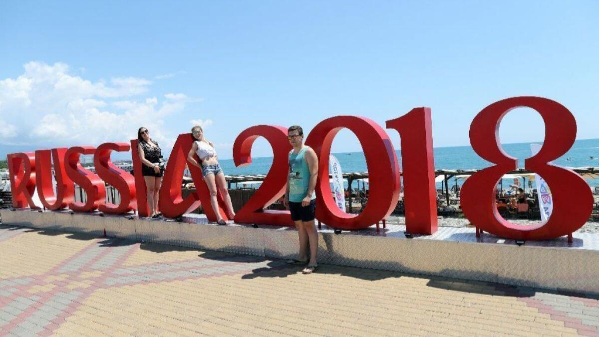 Soccer fans pose next to World Cup sign near Sochi stadium in Sochi, Russia.