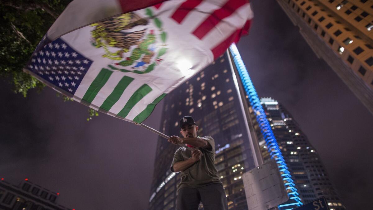 A protester waves a flag composed of elements of the U.S. and Mexican flags in front of the InterContinental in downtown Los Angeles, where President Trump stayed the night of March 13.