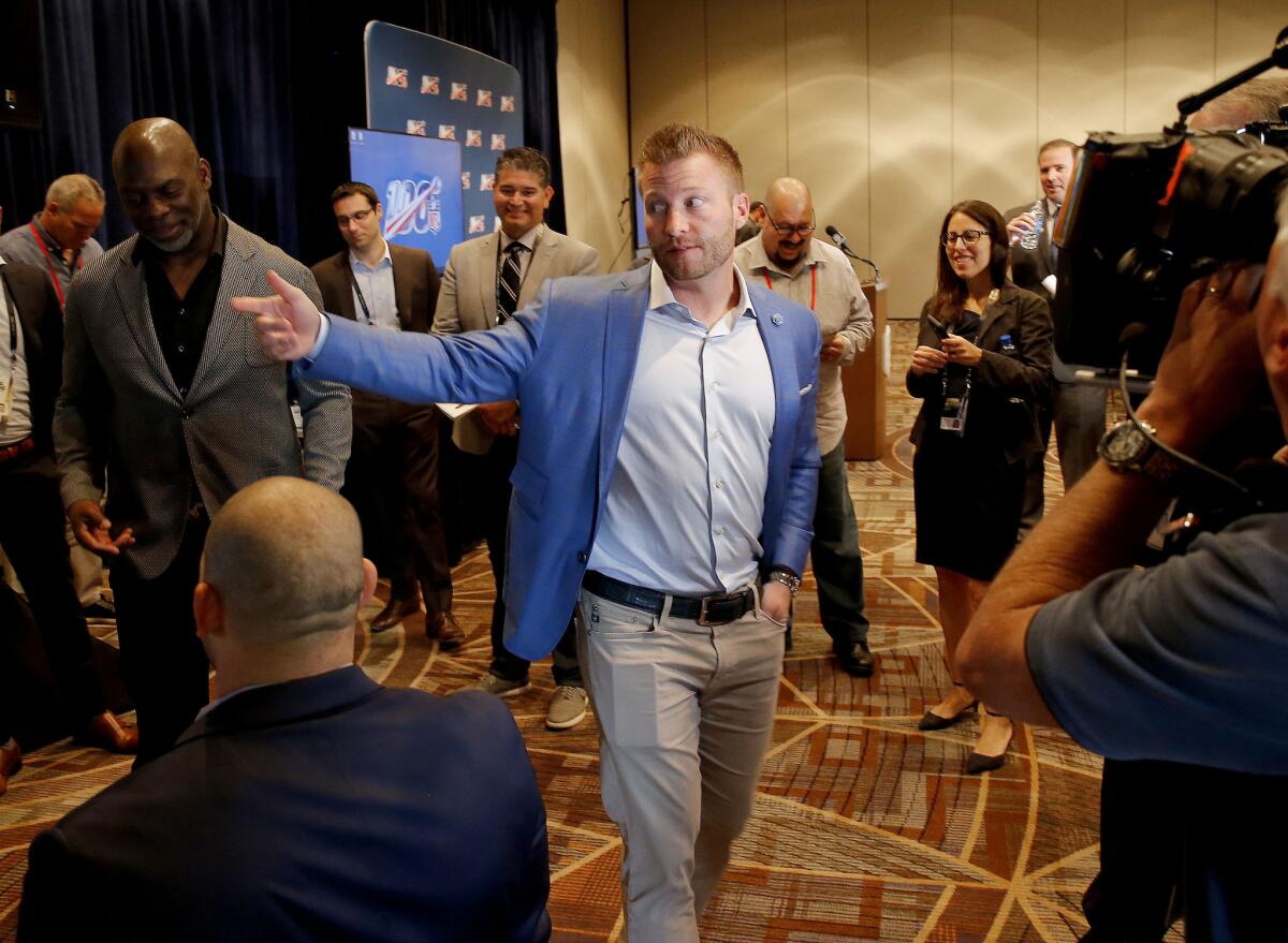 Rams coach Sean McVay, center, and  Chargers coach Anthony Lynn, left, walk through the halls during 2019 NFL meetings.
