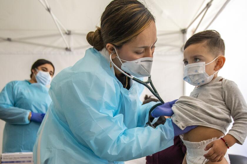 LOS ANGELES, CA - JANUARY 27: (Editor's note: This photo is initially for a Hayley Smith story.) Dr. Faraiba Faqeerzada PA-C (FP), left, examines two year Benjamin Salazar at South Central Family Health Center on Thursday, Jan. 27, 2022 in Los Angeles, CA. The center is located in a neighborhood with the highest Omicron case rates in the county. Benjamin has been having an upset stomack the last few days and his mother brought him in to get checked out. (Francine Orr / Los Angeles Times)