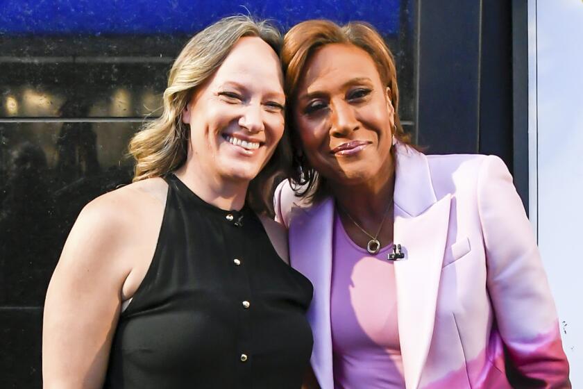 Amber Laign and Robin Roberts smile while leaning their heads together