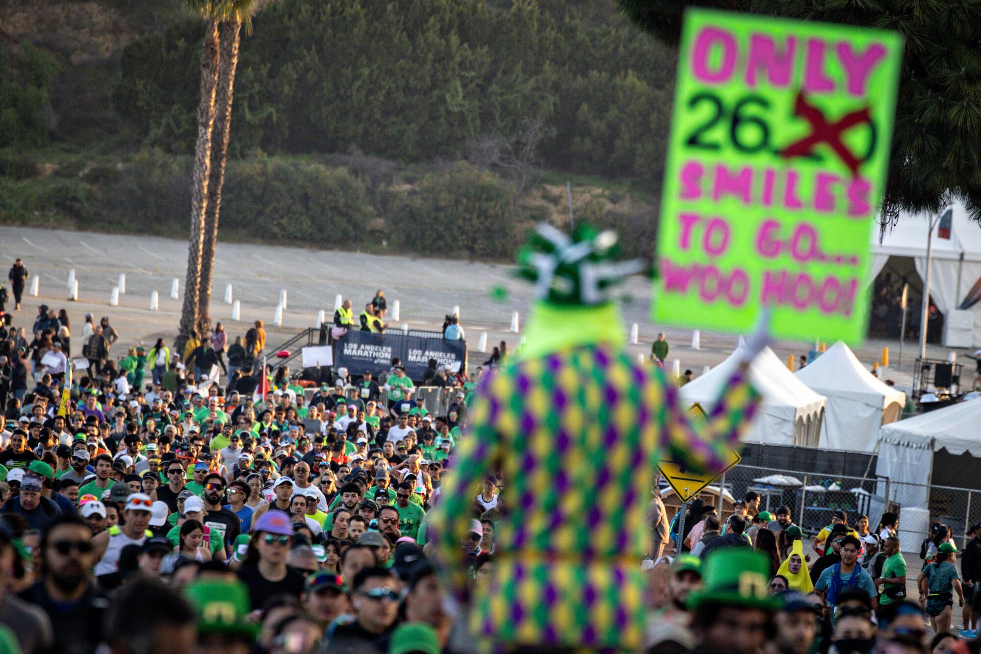 Un homme tient une pancarte indiquant "Seulement 26,2 sourires à emporter" au Marathon de Los Angeles.