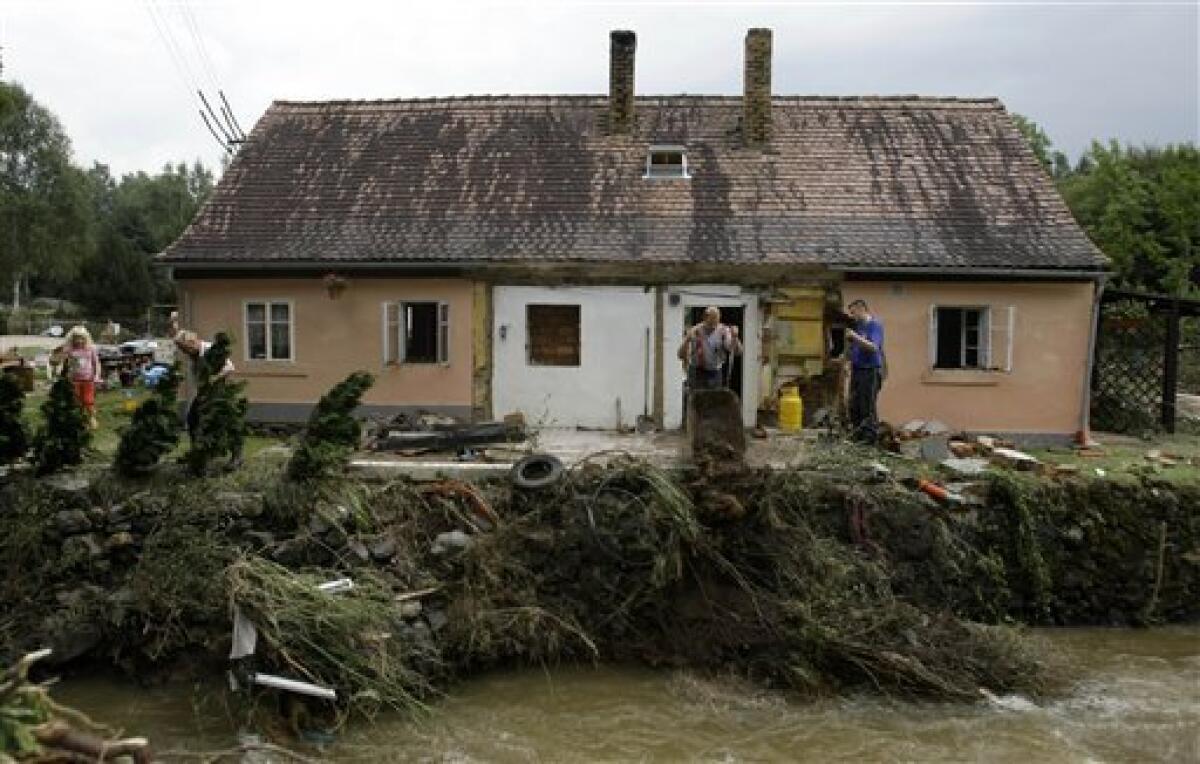 Residents clean their damaged house after flash floods hit the village of Hermanice, Czech Republic, Sunday, Aug. 8, 2010. The flooding has struck an area near the borders of Poland, Germany and the Czech Republic. (AP Photo/Petr David Josek)