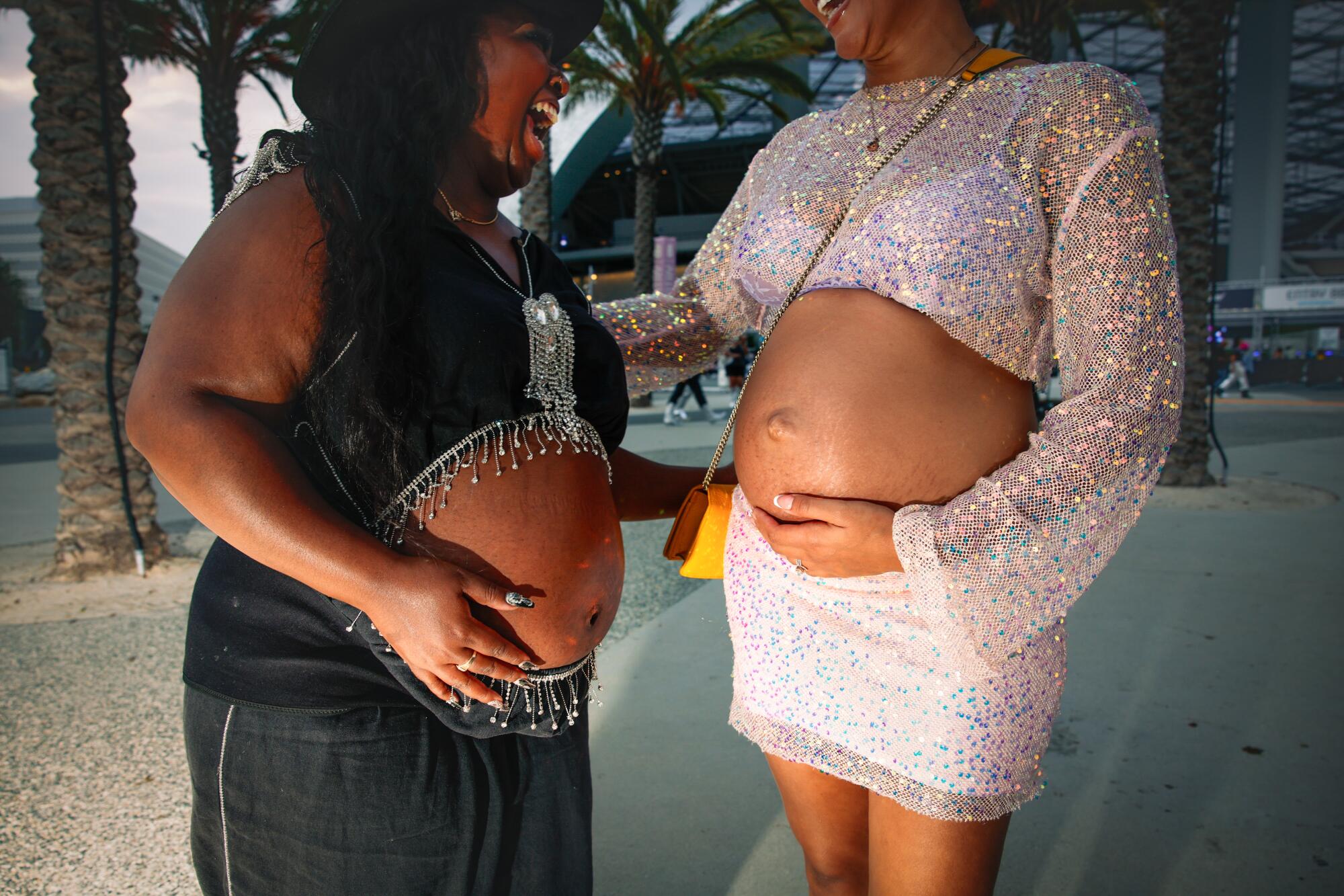 Two pregnant women pose at a concert