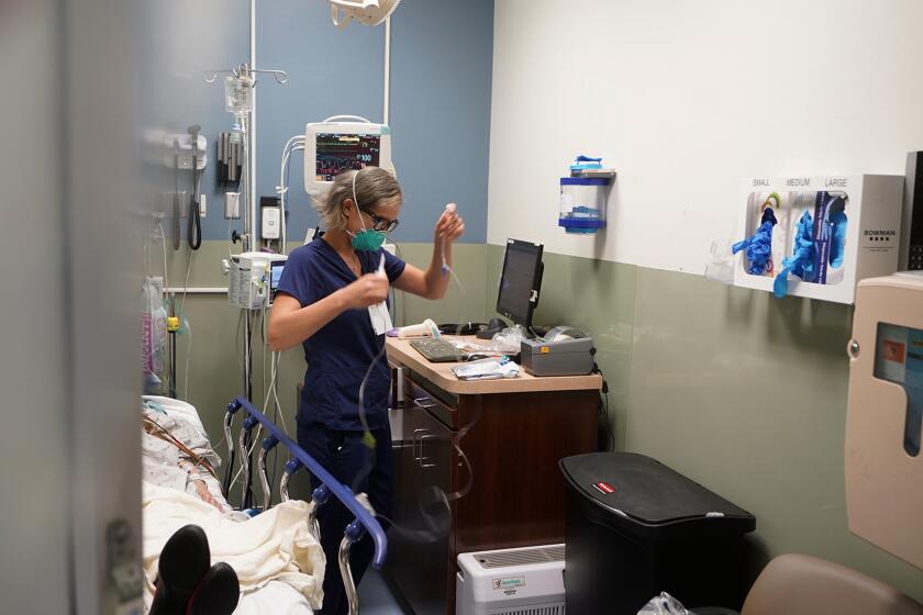 FILE - Registered nurse Sandra Younan sets up a new intravenous line for a patient under her care at Providence Cedars-Sinai Tarzana Medical Center in the Tarzana neighborhood of Los Angeles on March 11, 2021. A new rule in California aims to limit health care price increases to just 3% each year. The Health Care Affordability Board approved the rule on Wednesday, April 24, 2024. It sets a statewide cost growth target of 3% each year. (AP Photo/Damian Dovarganes, File)