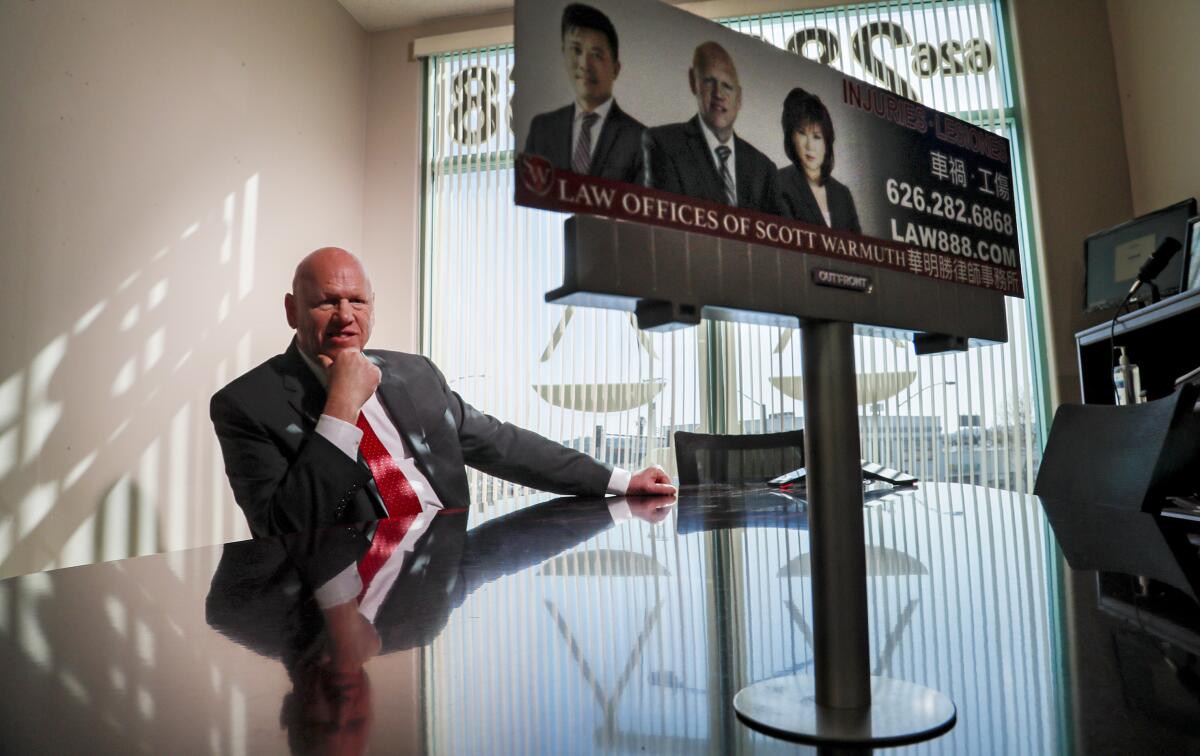 Scott Warmuth sits at desk with a small replica of a billboard ad.