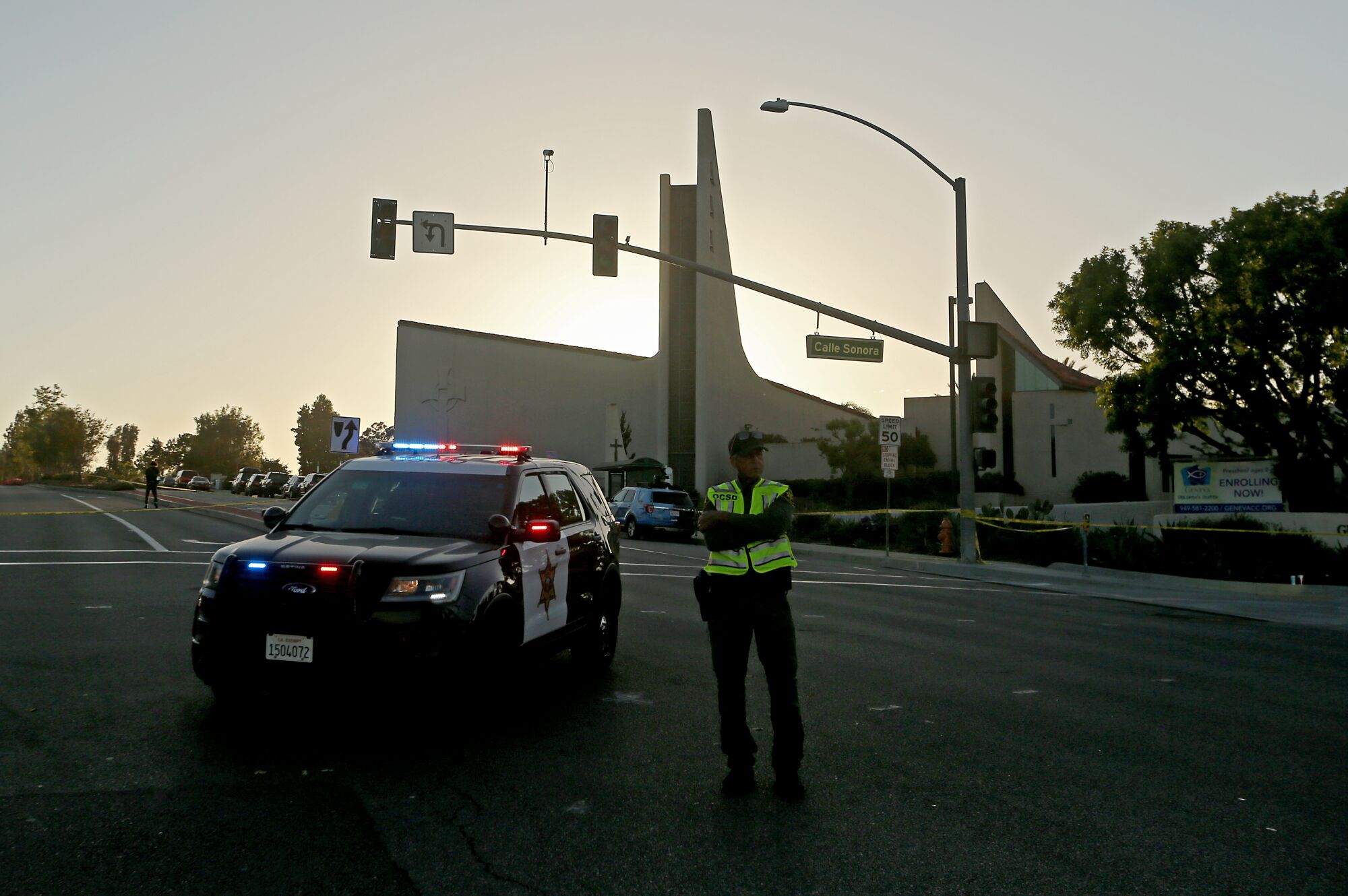 A sheriff's deputy standing beside a vehicle outside the church