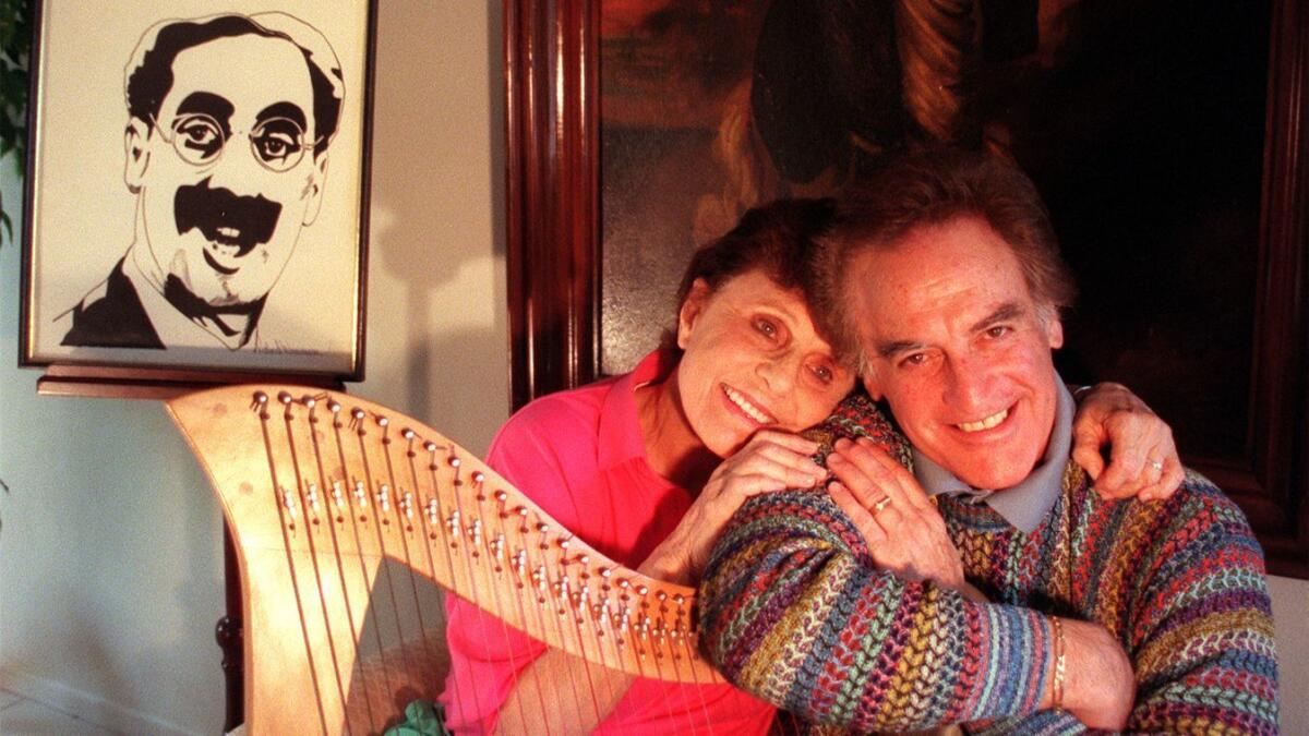 Miriam Marx Allen and her cousin Bill Marx, son of Harpo Marx, lean on a harp that Harpo used to play.
