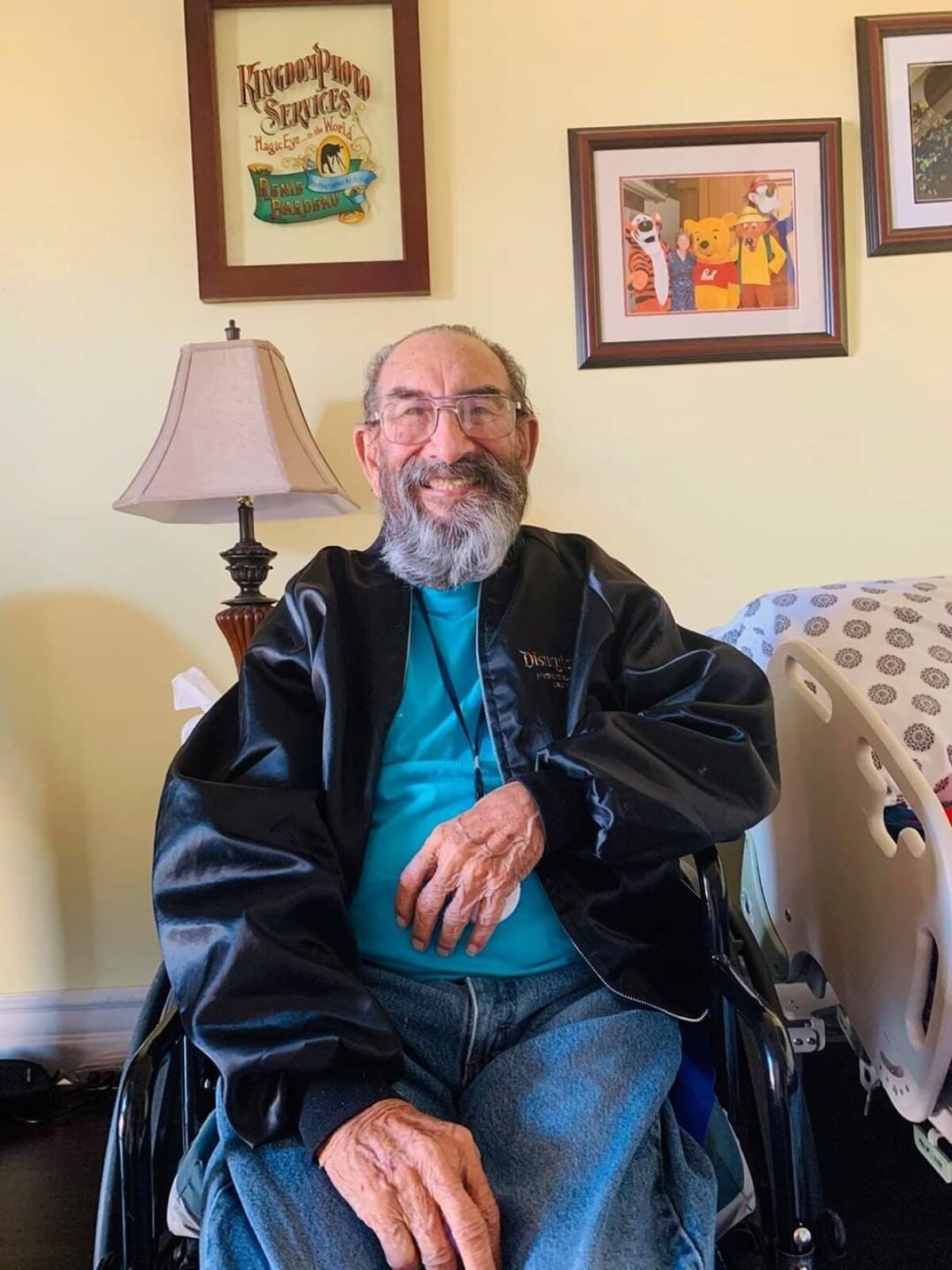 A bearded, smiling Renie Bardeau sits indoors in a wheelchair.