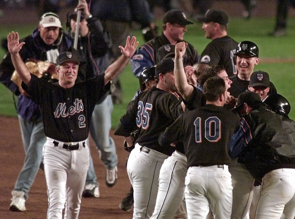 FILE - New York Mets manager Bobby Valentine (2) throws his arms up as his team celebrates on the field after Mets' Robin Ventura's grand slam-turned single in the 15th inning to defeat the Atlanta Braves 4-3 in Game 5 of the NL Championship Series in New York, in this Sunday, Oct. 17, 1999, file photo. For the Mets, July 30 will be a dark day — in a good way. New York will use black jerseys for the first time since 2012 when the Mets play Cincinnati at Citi Field that night. The Mets said Thursday, July 15, 2021, that they will use black jerseys for all remaining Friday night home games this season. (AP Photo/Chris Gardner, File)