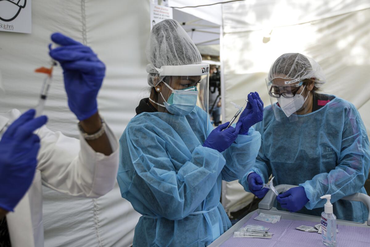 Nurse Cherry Costales, center, prepares COVID-19 vaccination at St. John's Well Child & Family Center.