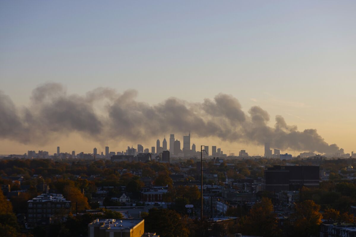 Smoke rises from a fire at the Delaware Valley Asphalt and Recycling Center on Tuesday, Nov. 9, 2021, in Philadelphia. (Tyger Williams/The Philadelphia Inquirer via AP)