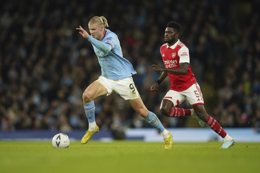 Manchester City's Erling Haaland, left, dribbles past Arsenal's Thomas Partey during the English FA Cup 4th round soccer match between Manchester City and Arsenal at the Etihad Stadium in Manchester, England, Friday, Jan. 27, 2023. (AP Photo/Dave Thompson)