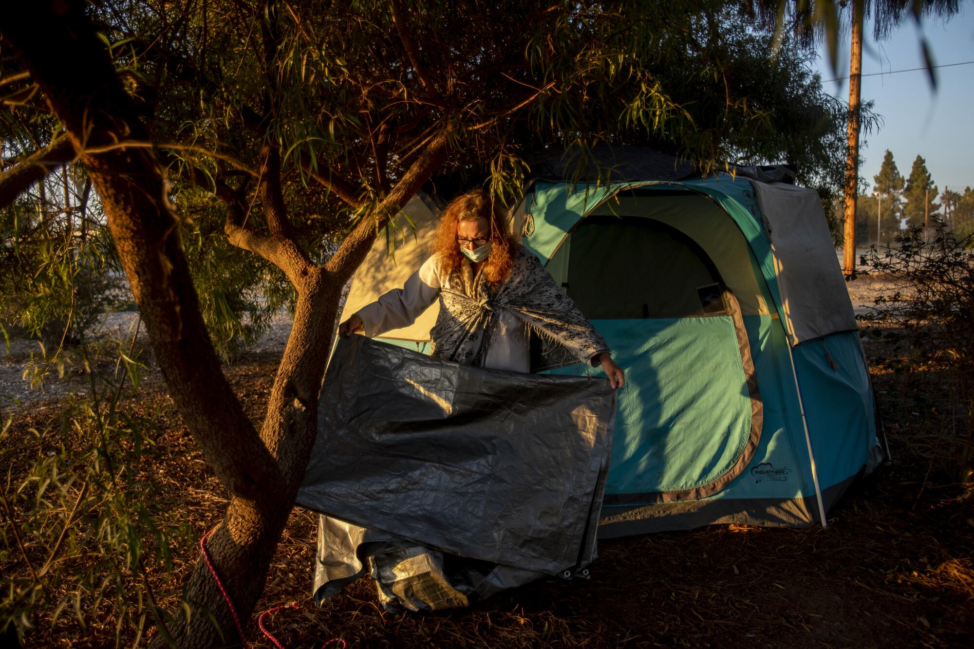 Nancy Wood, 75, folds a tarp she uses to block the wind at her tent in a Fountain Valley park. 