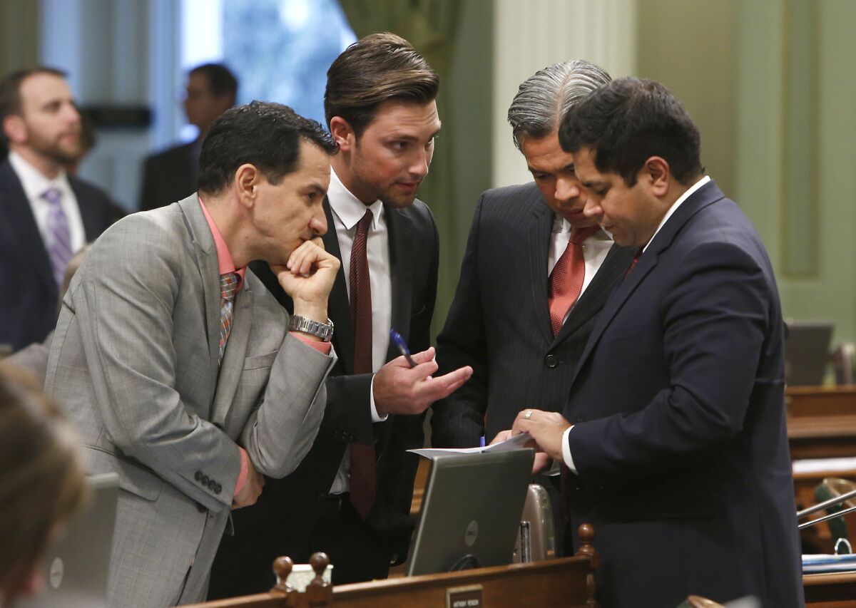 Democratic Assembly members, from left, Anthony Rendon of Lakewood, Ian Calderon, of Whittier, Rob Bonta of Alameda and Jimmy Gomez of Los Angeles, huddle during an Assembly session last year. Ian Calderon has agreed to pay fines for not disclosing income.