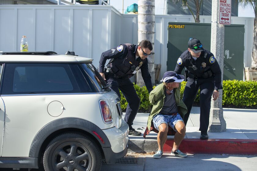 Newport Beach Police officers arrest a man who allegedly drove his car through a peaceful crowd during a Black Lives Matter supportive protest on the Balboa Peninsula on Wednesday, June 3.