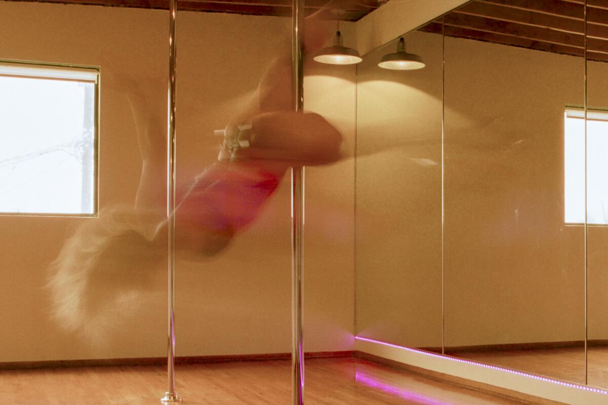 Two women pole dancing in a dance studio