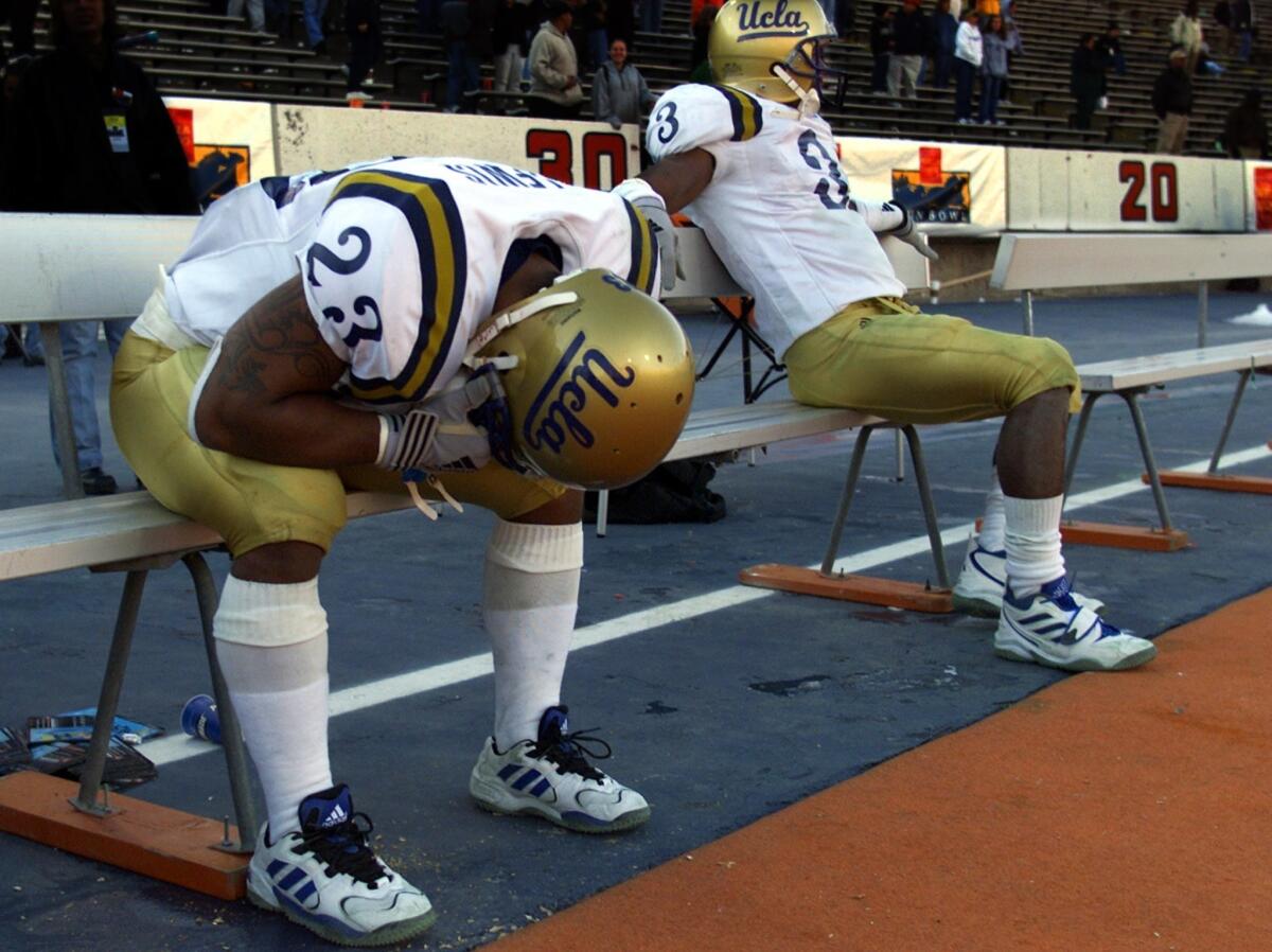 UCLA tailback Jermaine Lewis, left, sits on the bench with his head in his hands next to wide receiver Freddie Mitchell following the Bruins' 21-20 loss to Wisconsin in the 2000 Sun Bowl.
