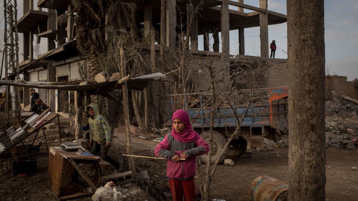 A young girl stands in front of a destroyed building in Hajin, Syria. Civilians have begun returning to some small towns close to Bagouz that were recently liberated by the U.S.-led coalition and the Syrian Democratic Forces.
