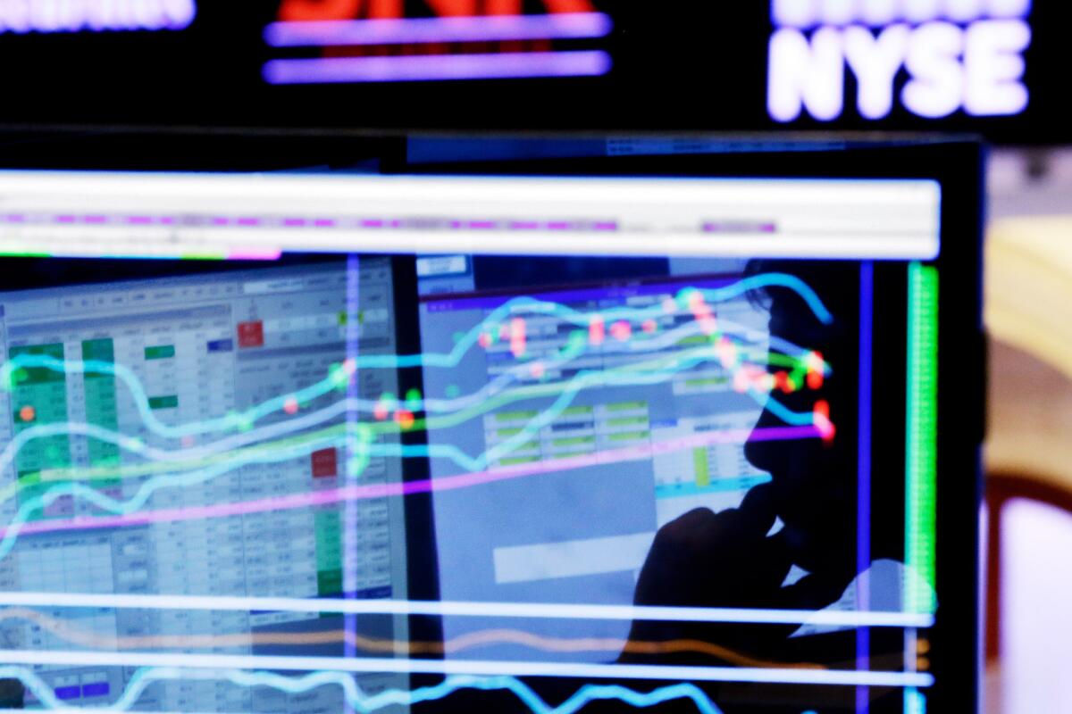 Specialist Anthony Rinaldi is silhouetted on a screen at his post on the floor of the New York Stock Exchange on Jan. 11.
