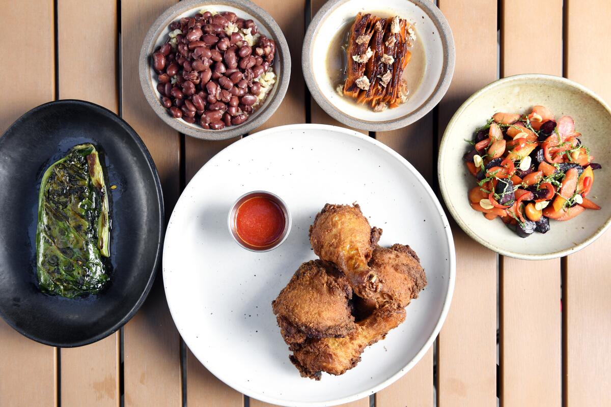 Skillet fried chicken with sides of collard greens, glazed carrot, candied yam gratin, rice and beans.