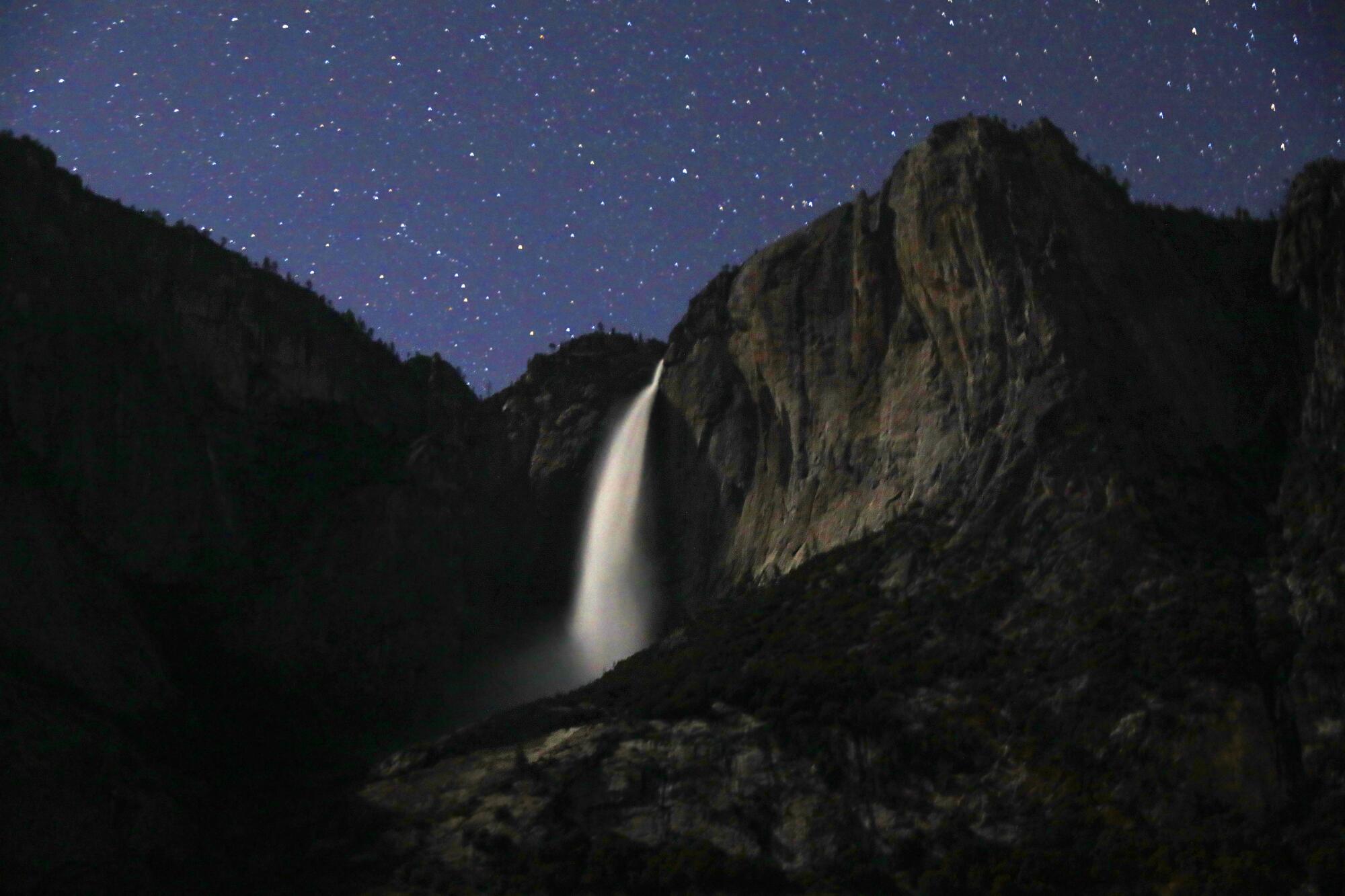 A large waterfall under a starry nighttime sky