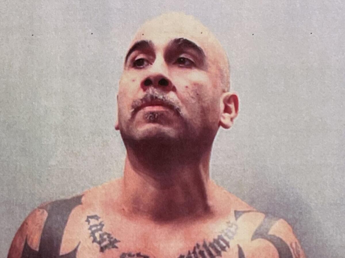 A bald man with a mustache and tattoos below his neck 