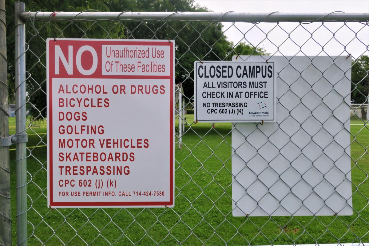 Signs on a  fence at Costa Mesa's Harper Park warn against trespassing but don't explain why the fence was installed.