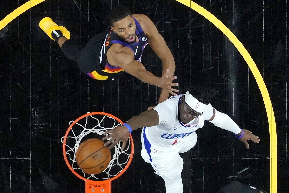 Clippers guard Reggie Jackson dunks as he glides past Suns forward Mikal Bridges defends during Game 5.