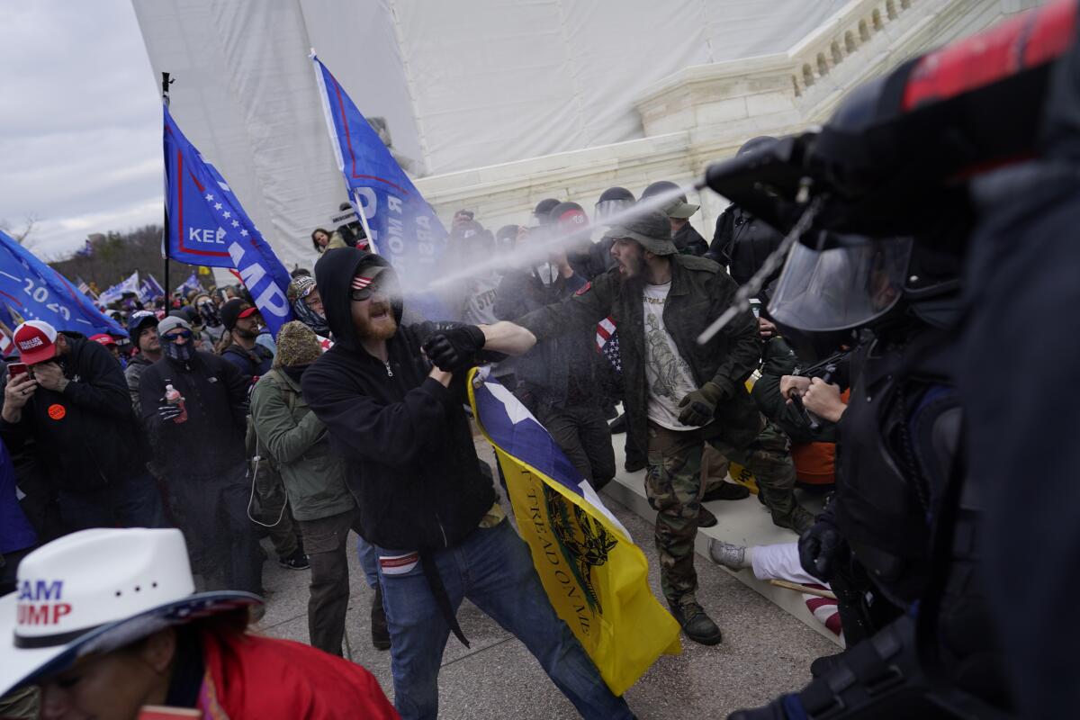 Protesters are sprayed with paper spray as they attempt to force their way through a police barricade in front of the Capital