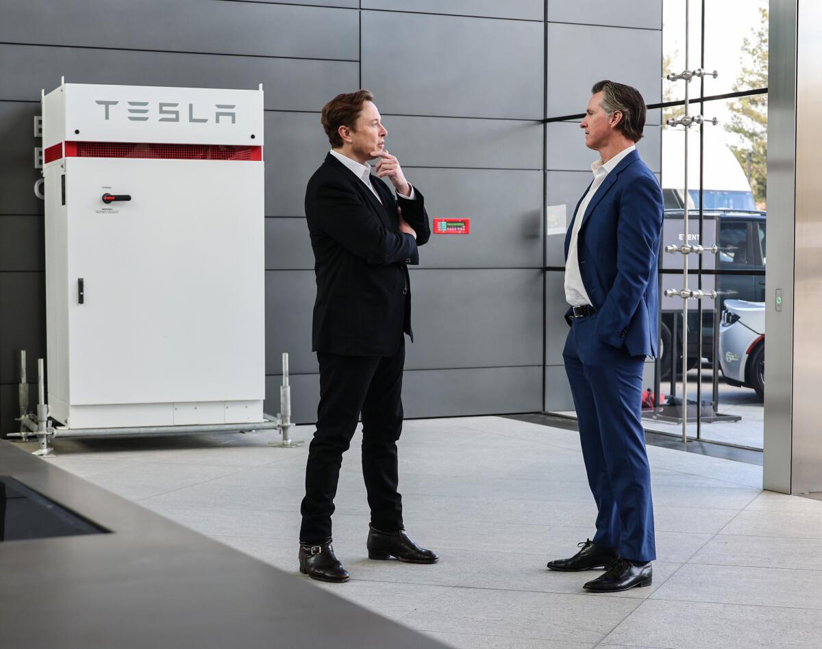 Gov. Gavin Newsom and Elon Musk stand facing each other