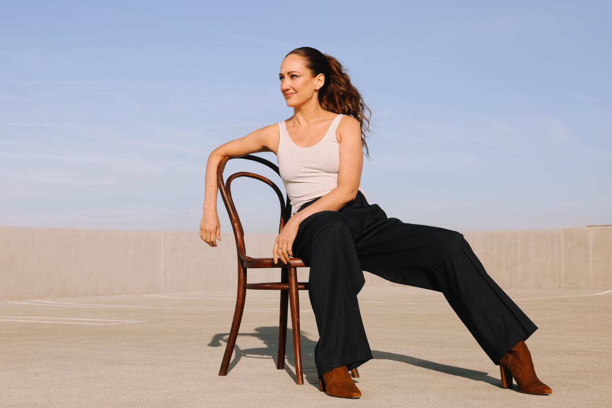 Woman sitting in a chair in front of a desert sand and blue sky background