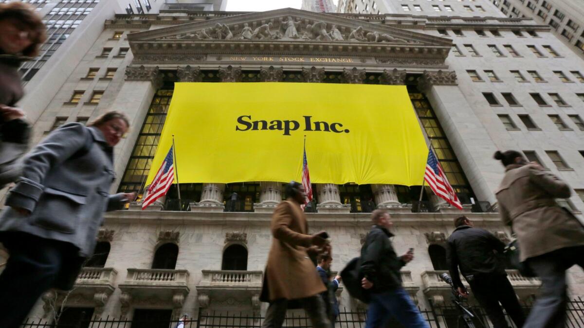 People walk past the New York Stock Exchange, which bears a banner for the Snap IPO.
