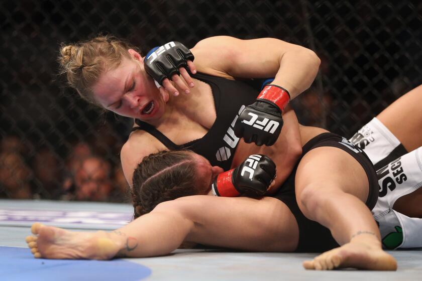 Ronda Rousey, about to submit Liz Carmouche, won her debut bout at Honda Center during UFC 157.