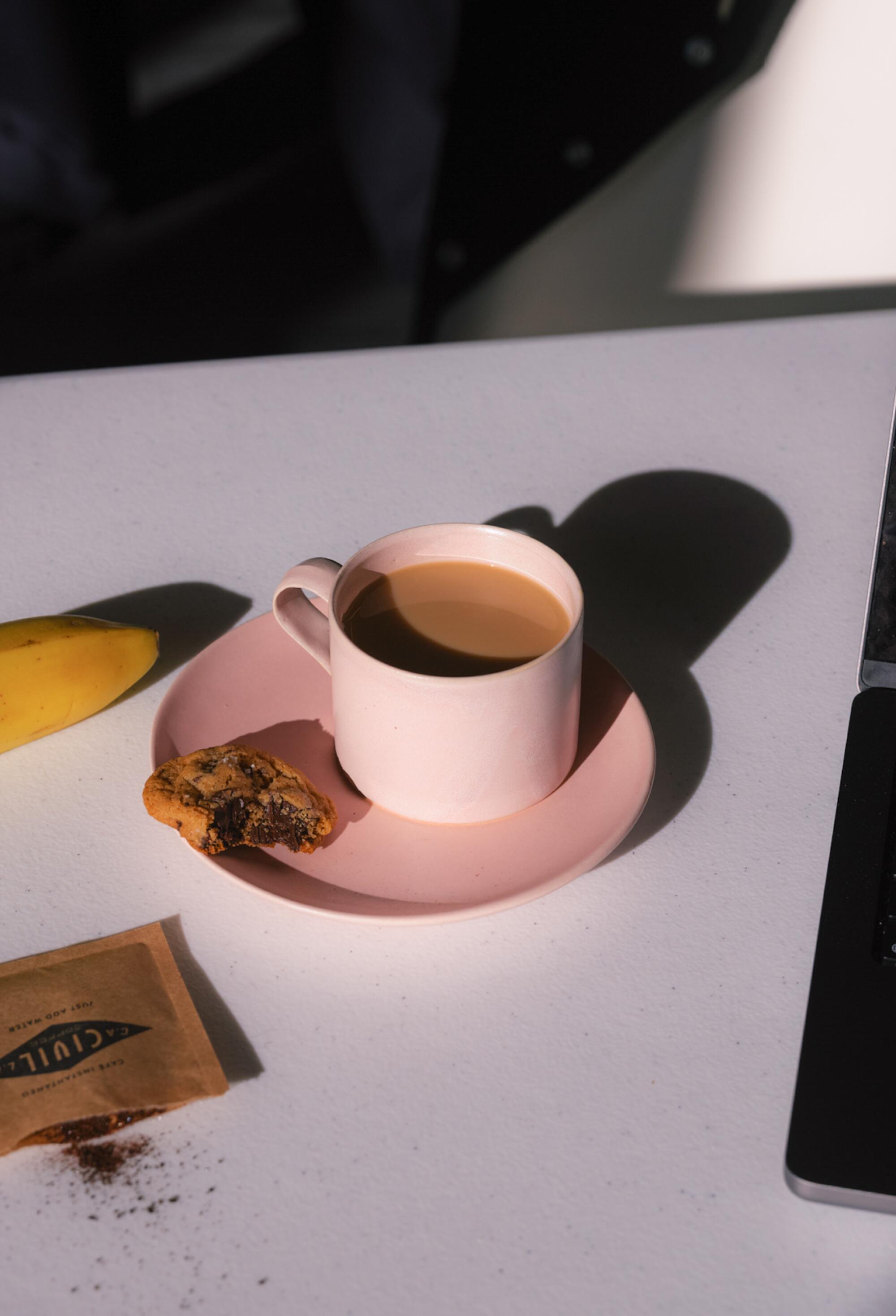 A coffee cup sits on a tabletop in a breakfast scene.