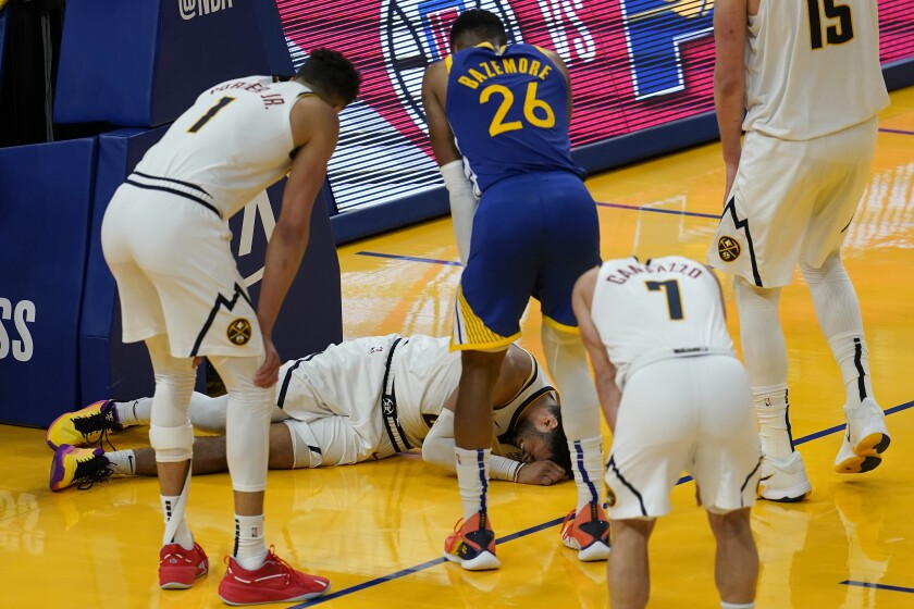 Players watch as Denver Nuggets guard Jamal Murray remains on the floor after being injured during the second half of an NBA basketball game against the Golden State Warriors in San Francisco, Monday, April 12, 2021. (AP Photo/Jeff Chiu)
