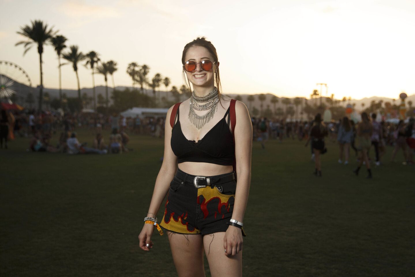 Sophia Arbess, 18, of New York, drew inspiration from everywhere with an old western-style belt buckle, huge '70s-inspired shade, a glamorous chandelier necklace and fire-printed shorts that call to mind the race track, as she poses for a portrait during weekend one of the three-day Coachella Valley Music and Arts Festival at the Empire Polo Grounds on Saturday, April 15, 2017 in Indio, Calif. (Patrick T. Fallon/ For The Los Angeles Times)