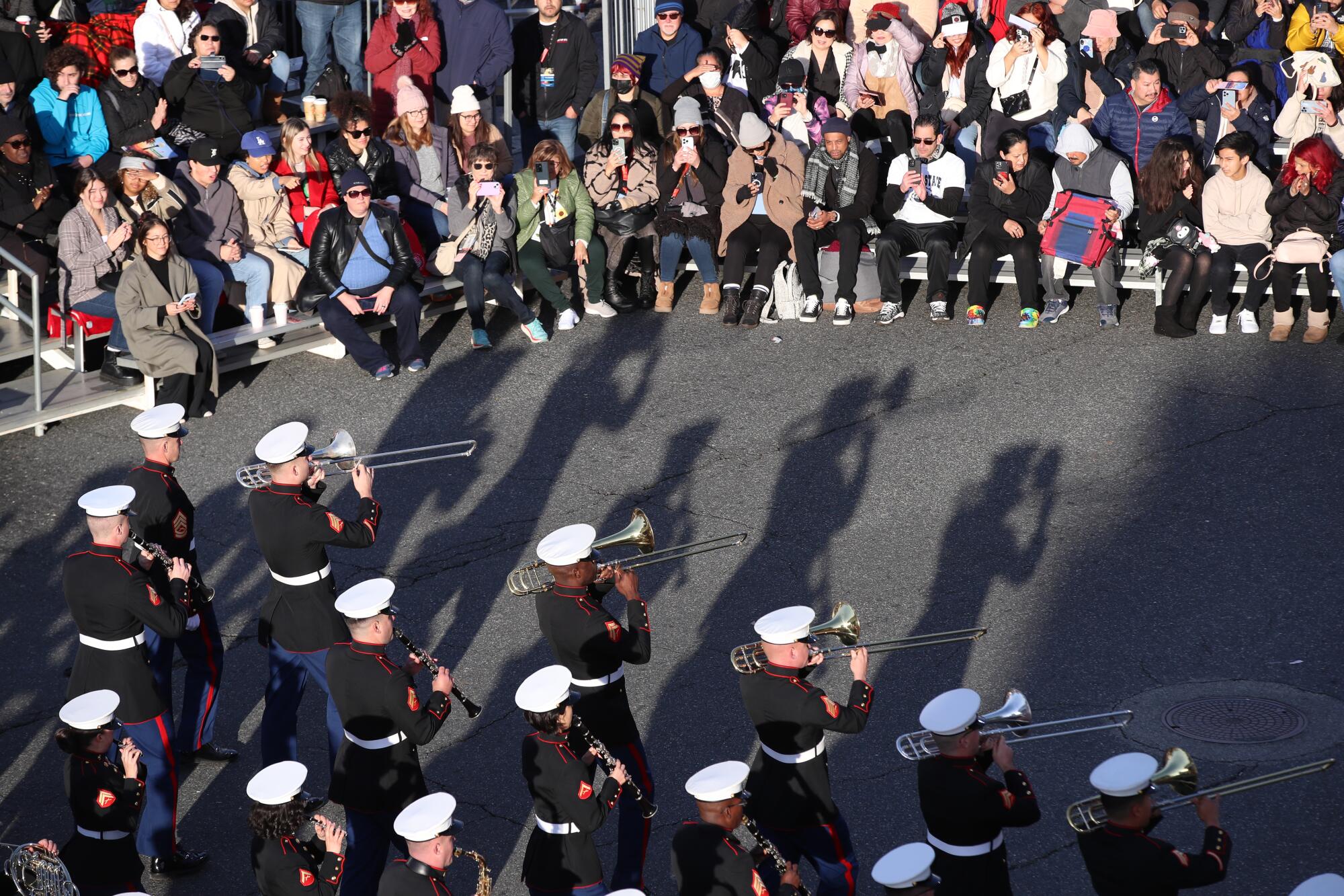 Marines in a marching band cast shadows on the Rose Parade route.