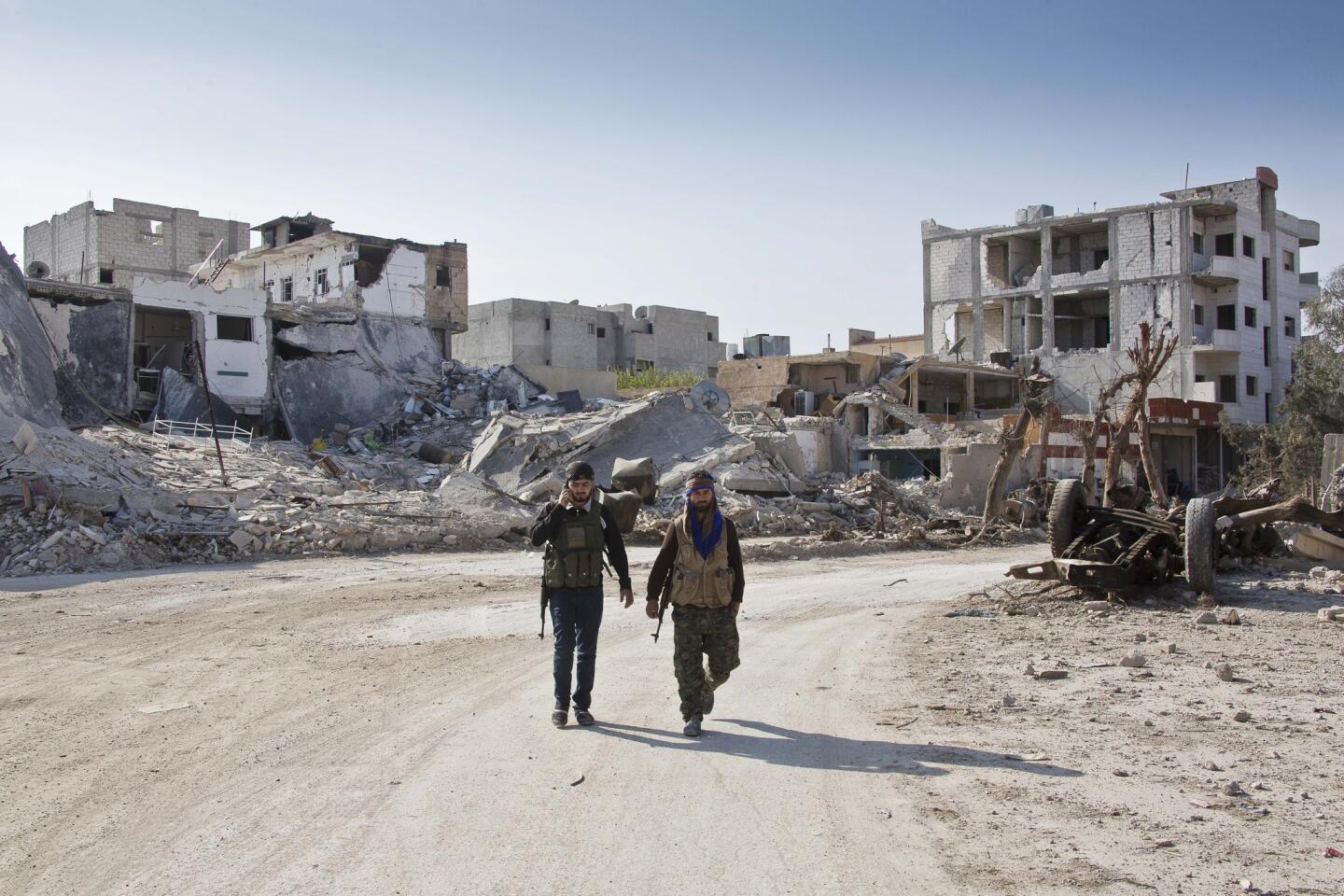 Kurdish soldiers walk near the town entrance circle heading to their strongholds in Kobani, Syria.