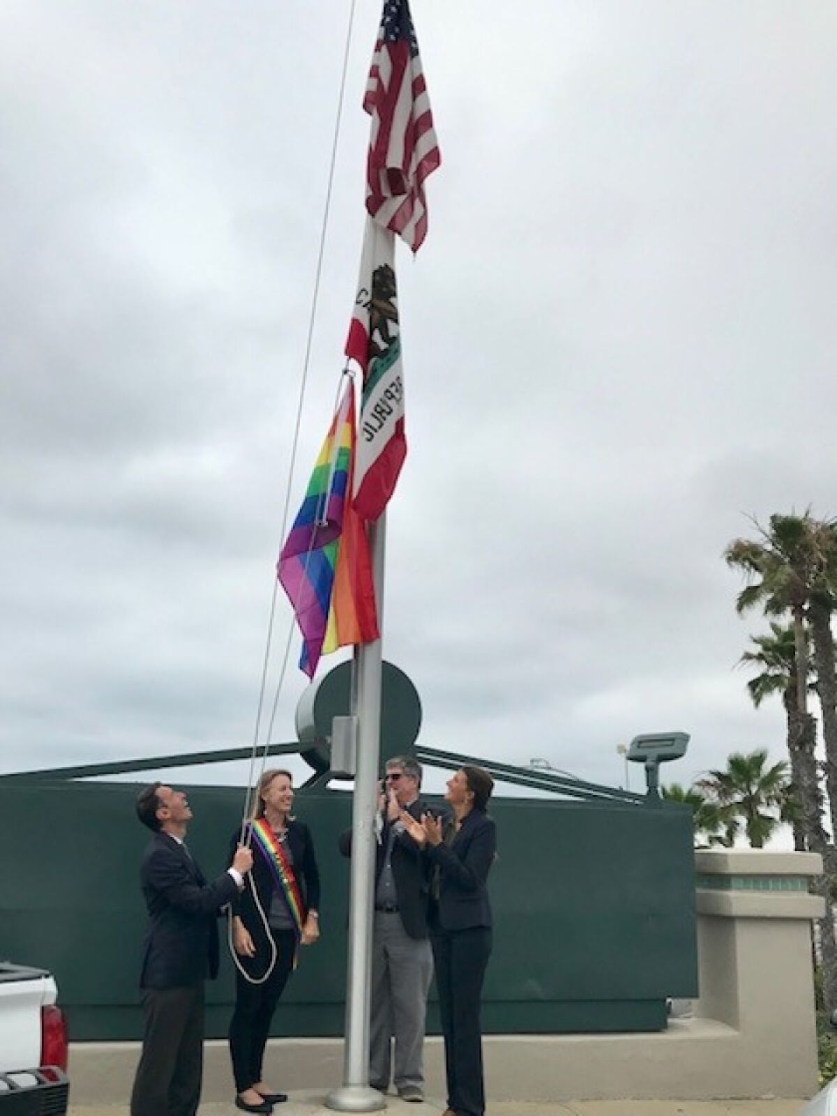 Encinitas Councilman Joe Mosca launches the pride flag skyward, as Mayor Catherine Blakespear, Councilman Tony Kranz and Councilwoman Kellie Shay Hinze celebrate Wednesday afternoon.
