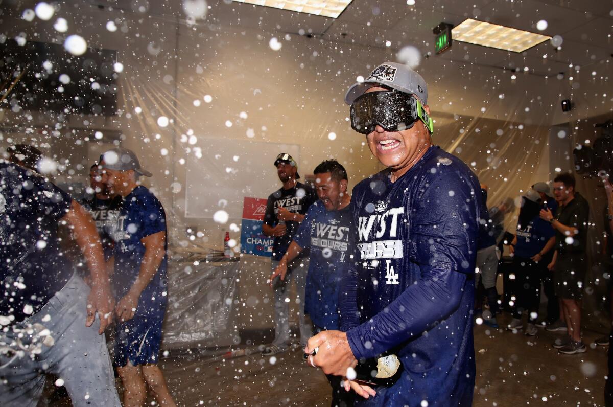 Dodgers manager Dave Roberts celebrates by spraying champagne with players in the locker room 