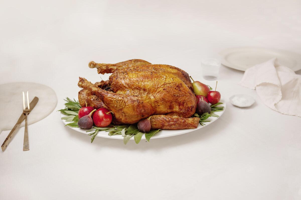 Whole roast turkey on a white plate on a white tablecloth.