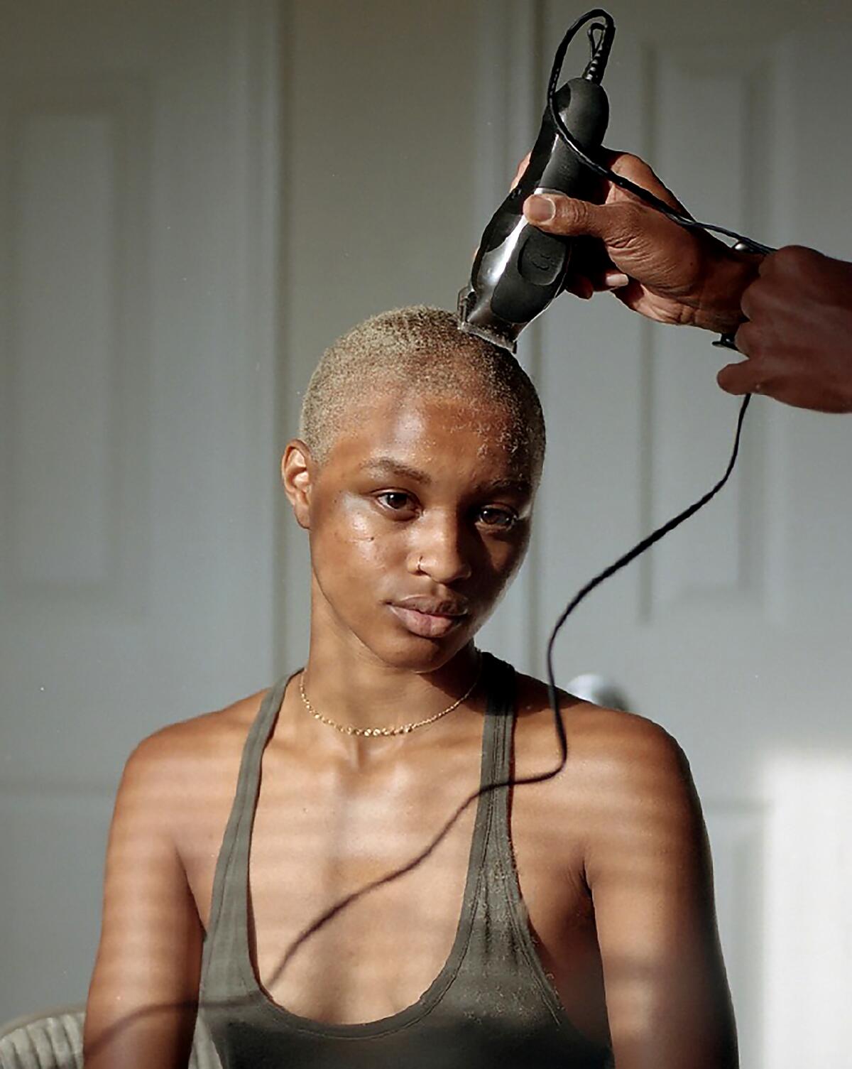 A portrait of a woman getting her hair buzzed