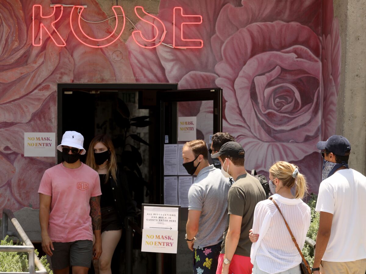 Customers wearing face masks wait in line at the Rose restaurant in Venice