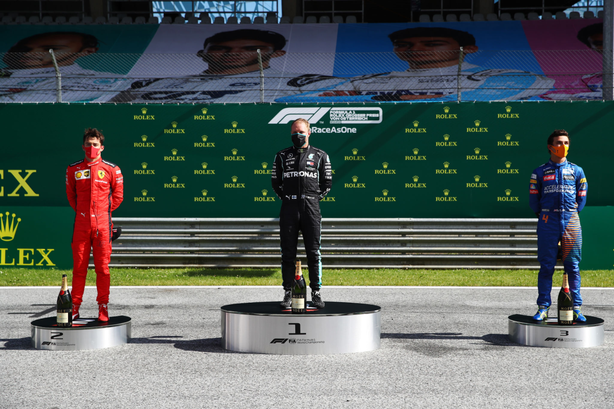 Valtteri Bottas, center, stands between second-place finisher Charles Leclerc, left, and third placed Lando Norris