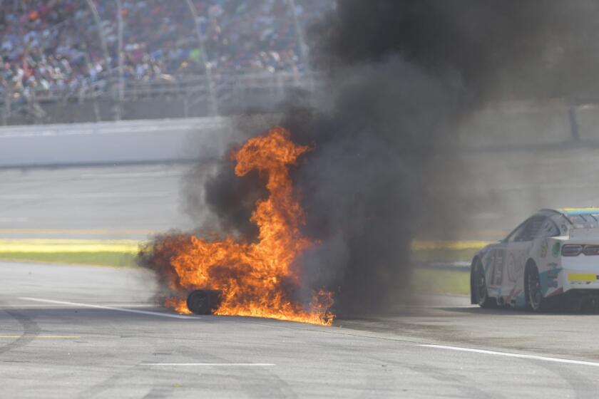 Cars drive by a gas can fire on pit row during a NASCAR Cup Series auto race at Talladega Superspeedway, Sunday, Oct. 1, 2023, in Talladega, Ala. (AP Photo/Julie Bennett)