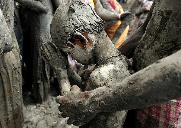 A young Indian Hindu pilgrim joins in prayers after bathing in the mud of a dried up pond believed to have holy, restorative powers in Nakali village, south of Kolkata.