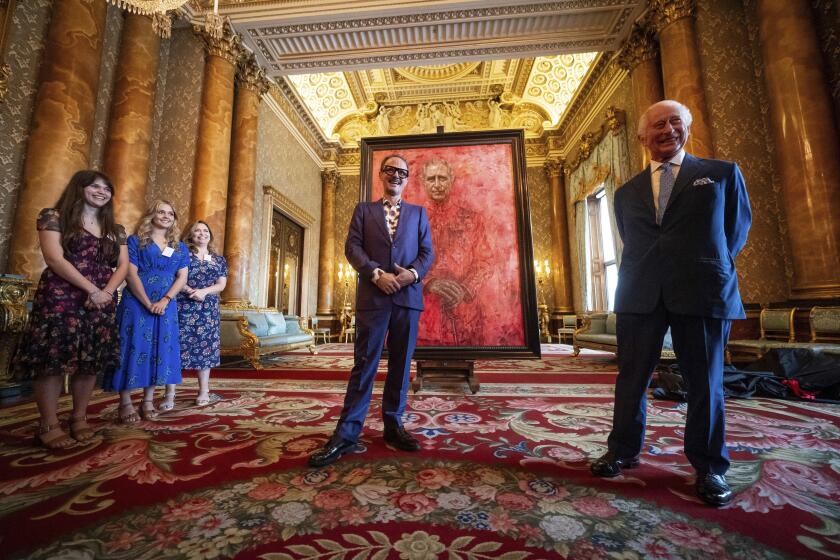Artist Jonathan Yeo, center, and Britain's King Charles III at the unveiling of Yeo's portrait of the King, in the blue drawing room at Buckingham Palace, in London, Tuesday May 14, 2024. The portrait was commissioned in 2020 to celebrate the then Prince of Wales's 50 years as a member of The Drapers' Company in 2022. The artwork depicts the King wearing the uniform of the Welsh Guards, of which he was made Regimental Colonel in 1975. The canvas size - approximately 8.5 by 6.5 feet when framed - was carefully considered to fit within the architecture of Drapers' Hall and the context of the paintings it will eventually hang alongside. (Aaron Chown/Pool Photo via AP)