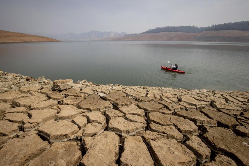 FILE - A kayaker paddles in Lake Oroville as water levels remain low due to continuing drought conditions in Oroville, Calif., on Aug. 22, 2021. The American West's megadrought deepened so much last year that it is now the driest it has been in at least 1200 years and a worst-case scenario playing out live, a new study finds. (AP Photo/Ethan Swope, File)