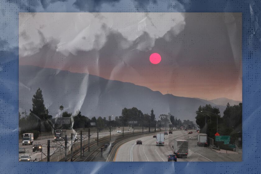 Smoke from wildfires darkens the sky over the mountains and freeway.